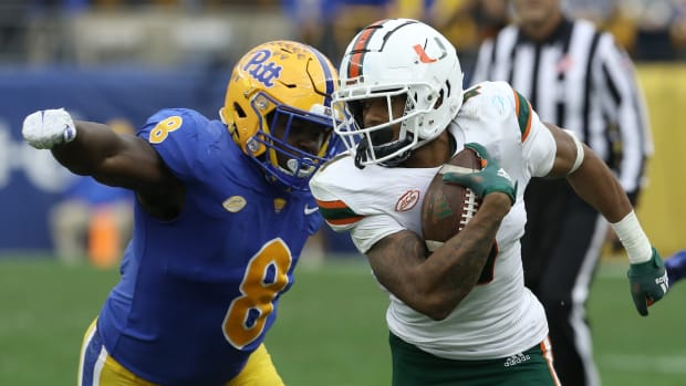 Oct 30, 2021; Pittsburgh, Pennsylvania, USA; Miami Hurricanes running back Jaylan Knighton (4) runs against Pittsburgh Panthers defensive lineman Calijah Kancey (8) after a catch during the fourth quarter at Heinz Field. Miami won 38-34. Mandatory Credit: Charles LeClaire-USA TODAY Sports